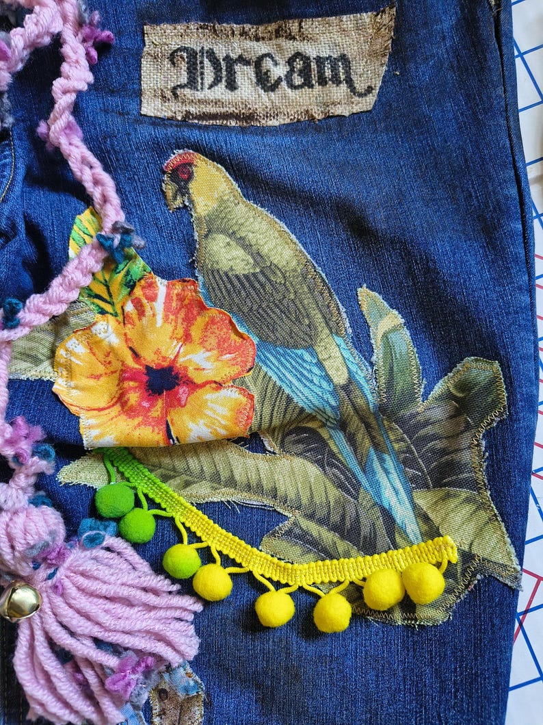 Patchwork Boho AppliquePatched Upcycled Cropped DarkerDenim Cuffed or Straight Jeans SIZE 14 TO 16 Stretch VintageStyledenim.   Inseam 26.  Vintage-look handpainted throughout Flowers, Birds, Cat, and appliques of various designs.  Handmade and handcrafted.   Unique Applique Jeans Distressed.  Highrise High Waisted, Handpainted Handmade Appliqued Straight Style Jeans. Size 14 to 16 depending on your measurements.  Check the measurements.  Handmade Boho Sash Bohemian design crocheted with bells.