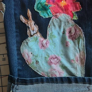 Patchwork Boho AppliquePatched Upcycled Cropped DarkerDenim Cuffed or Straight Jeans SIZE 14 TO 16 Stretch VintageStyledenim.   Inseam 26.  Vintage-look handpainted throughout Flowers, Birds, Cat, and appliques of various designs.  Handmade and handcrafted.   Unique Applique Jeans Distressed.  Highrise High Waisted, Handpainted Handmade Appliqued Straight Style Jeans. Size 14 to 16 depending on your measurements.  Check the measurements.  Handmade Boho Sash Bohemian design crocheted with bells.