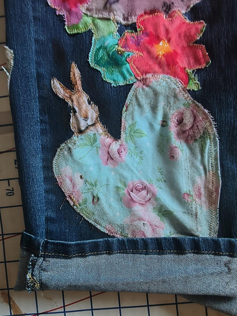 Patchwork Boho AppliquePatched Upcycled Cropped DarkerDenim Cuffed or Straight Jeans SIZE 14 TO 16 Stretch VintageStyledenim.   Inseam 26.  Vintage-look handpainted throughout Flowers, Birds, Cat, and appliques of various designs.  Handmade and handcrafted.   Unique Applique Jeans Distressed.  Highrise High Waisted, Handpainted Handmade Appliqued Straight Style Jeans. Size 14 to 16 depending on your measurements.  Check the measurements.  Handmade Boho Sash Bohemian design crocheted with bells.