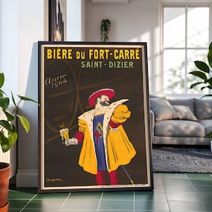 May include: A framed vintage advertisement for Bière du Fort-Carré beer, Saint-Dizier. The poster features a man in historical attire holding a beer. The poster has text in yellow and green, with the year 1544. The background is dark with beer barrels.