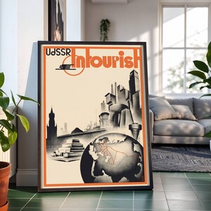 May include: Framed vintage travel poster with the text "USSR Intourist" in orange and black. The poster features a stylized illustration of a cityscape, a globe, and a red travel route. The poster is in a black frame.