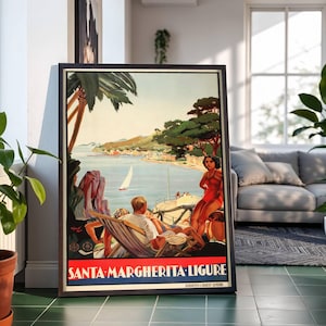 May include: Framed vintage travel poster for Santa Margherita Ligure, Italy. The poster shows a seaside scene with people relaxing, a sailboat, and the text "SANTA MARGHERITA-LIGURE". The poster has a black frame and is displayed indoors.