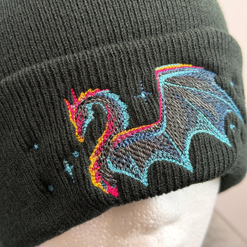 Unique Gift Beanie Dragon Embroidery Winter Hat Black Knit Cap Fantasy Design Mythical Creature Headwear Warm Fleece Lined Acrylic Material Unisex Fit Special Present Idea Cold Weather Accessory Blue Pink Thread Detail Gothic Style Element