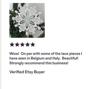 May include: A white lace snowflake ornament featuring intricate threadwork and a small central crystal accent. The snowflake has six symmetrical points with delicate, leaf-like patterns and a small loop at the top for hanging on a tree branch.