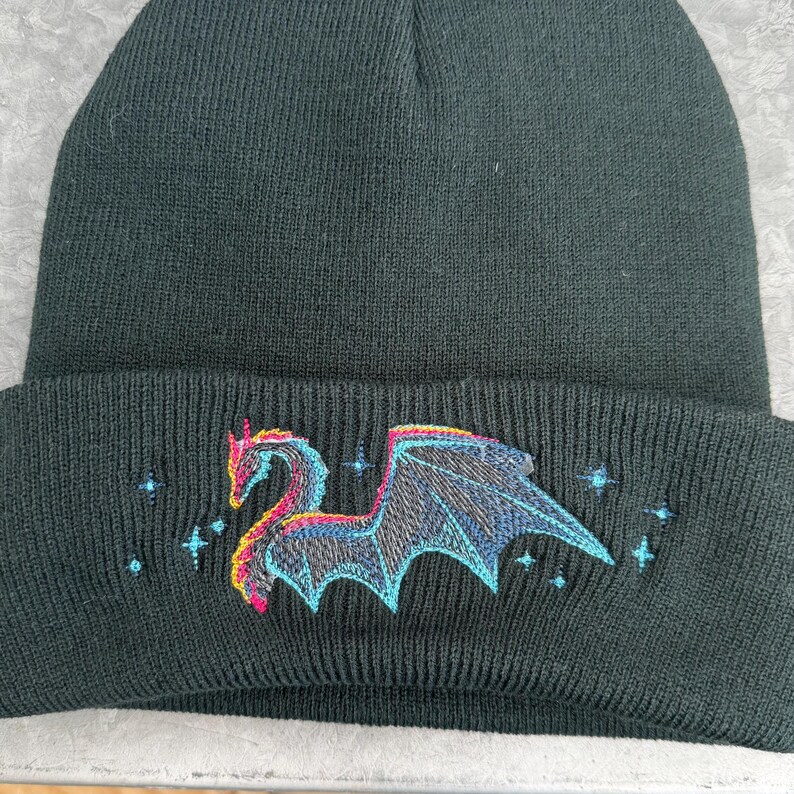 Fleece Lined Beanie Dragon Design Winter Hat Black Knit Material Soft Comfortable Headwear Embroidered Mythical Creature Warm Acrylic Cap Unisex Fit Cold Weather Protection Fantasy Inspired Accessory Gothic Style Element Blue Pink Thread