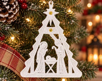 May include: A white embroidered Christmas tree ornament featuring a nativity scene with figures of Mary, Joseph, and the infant Jesus in a manger. The triangular frame is topped with a star and accented with two small, circular gold beads.