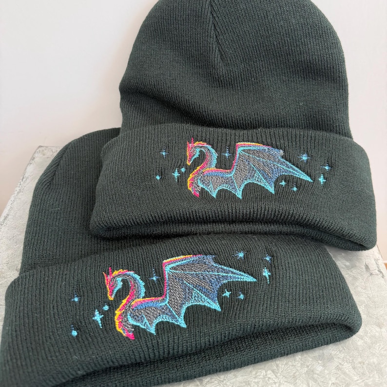 Dragon Winter Beanie Black Knit Hat Embroidered Design Mythical Creature Gothic Style Warm Headwear Fleece Lined Acrylic Material Unisex Fit Cold Weather Protection Fantasy Enthusiast Gift Blue Pink Embroidery Unique Pattern Stylish Look