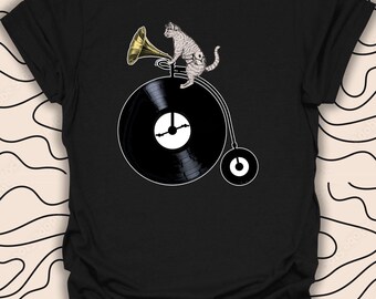 May include: Black t-shirt with a graphic of a cat riding a bicycle with a record as the wheel and playing a trumpet.