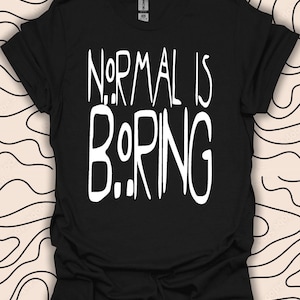 Puede incluir: Camiseta negra con texto blanco que dice "NORMAL IS BORING" en una fuente estilizada.