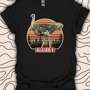 May include: Black t-shirt with a vintage-style illustration of an ostrich standing in front of a sunset. The text "ALLEGEDLY" is printed below the ostrich.