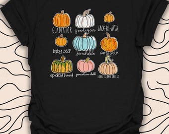 Puede incluir: Camiseta negra con un gráfico de diferentes tipos de calabazas con nombres como "Gladiator", "Gooligan", "Jack-Be-Little", "Baby Bear", "Jarrahdale", "Warty Goblin", "Speckled Hound", "Porcelain Doll" y "Long Island Cheese".