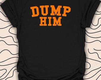 Puede incluir: Camiseta negra con el texto "DUMP HIM" en naranja.
