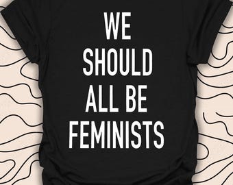 May include: Black t-shirt with white text that reads "We should all be feminists."