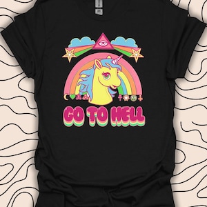 以下が含まれることがあります： 虹、ユニコーン、そして「GO TO HELL」という文字が書かれた黒いTシャツ。虹には平和の象徴、ハート、星、十字架、目など、さまざまなシンボルが組み込まれています。