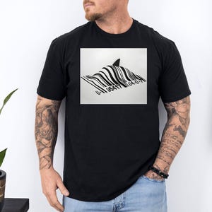 Peut inclure: T-shirt noir avec un motif graphique d'un aileron de requin émergeant d'un motif de code-barres. Le code-barres comprend les chiffres "0-95417 04-0-7". Le motif est centré sur le t-shirt.