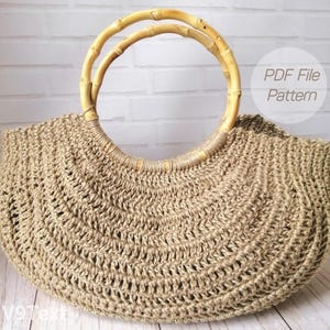 May include: A beige crocheted tote bag with bamboo handles. The bag has a rounded shape and a textured, open weave design. The handles are made of light-colored bamboo. The text "PDF File Pattern" is visible on the upper right.
