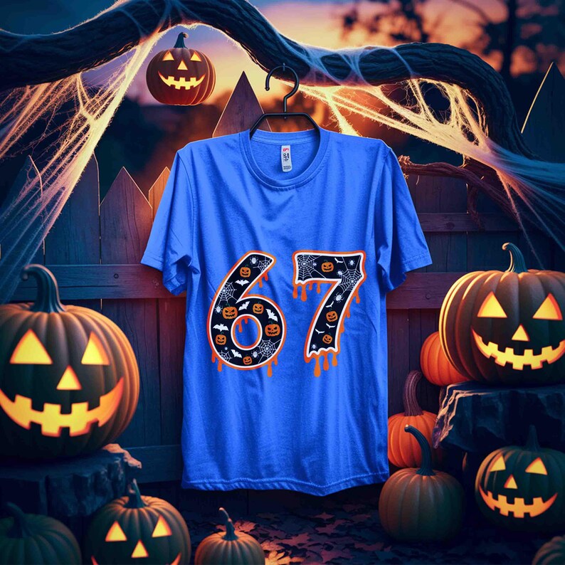 May include: A blue t-shirt with the number "67" in orange, decorated with spiderwebs and jack-o'-lanterns. The shirt is hanging on a black hanger, with carved pumpkins and a spooky Halloween scene in the background.