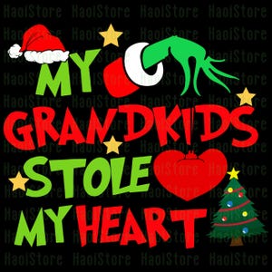 May include: A black graphic design with the text "MY GRANDKIDS STOLE MY HEART". The design includes a Santa hat, a green hand, stars, a red heart, and a Christmas tree. The text is in red and green.