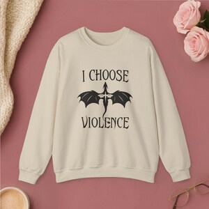 Comfortable navy crewneck sweatshirt. Striking white graphic design on the front features a majestic Dragon, boldly proclaiming the phrase I Chose Violence a statement that's sure to resonate with fans of intense, passionate relationships.