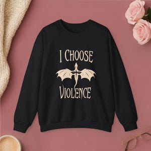 Comfortable white crewneck sweatshirt. Striking graphic design on the front features a majestic Black Dragon, boldly proclaiming the phrase I Chose Violence a statement that's sure to resonate with fans of intense, passionate relationships.