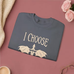 Comfortable light pink crewneck sweatshirt. Striking graphic design on the front features a majestic Black Dragon, boldly proclaiming the phrase I Chose Violence a statement that's sure to resonate with fans of intense, passionate relationships.