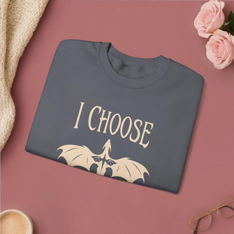 Comfortable light pink crewneck sweatshirt. Striking graphic design on the front features a majestic Black Dragon, boldly proclaiming the phrase I Chose Violence a statement that's sure to resonate with fans of intense, passionate relationships.