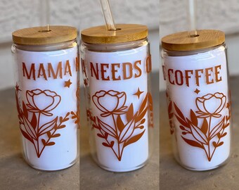 May include: Three glass tumblers with bamboo lids and reusable straws. The tumblers have a white background with a floral design and the text "Mama Needs Coffee".