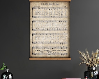 Könnte beinhalten: Ein Wandbehang im Vintage-Stil mit Notenblättern mit dem Titel "It Is Well With My Soul". Der Text ist auf gealtertem Papier gedruckt, und der Holzrahmen verleiht einen rustikalen Touch. Das Kunstwerk wird an einer dunkelgrauen Wand gezeigt.