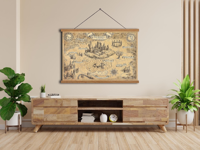 K&ouml;nnte beinhalten: Eine Karte von Hogwarts im Vintage-Stil, mit detaillierten Illustrationen des Schlosses und der Umgebung. Die Karte ist auf gealtertem Papier gedruckt und mit Holzleisten gerahmt, die an einer schwarzen Schnur aufgeh&auml;ngt sind. Ein dekoratives Element.