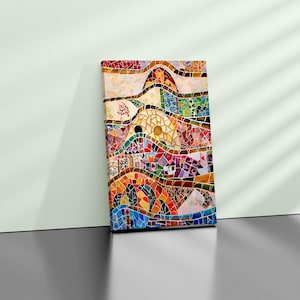 May include: A rectangular canvas print featuring a colorful mosaic design. The artwork showcases a vibrant mix of geometric shapes and patterns in shades of red, orange, yellow, green, blue, and purple. The print is leaning against a white wall.