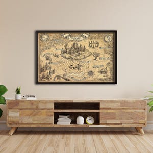 K&ouml;nnte beinhalten: Eine gerahmte Karte von Hogwarts mit detaillierten Illustrationen des Schlosses und seiner Umgebung. Die sepiafarbene Karte in einem schwarzen Rahmen wird an einer hellen Wand &uuml;ber einem Holzschrank ausgestellt.