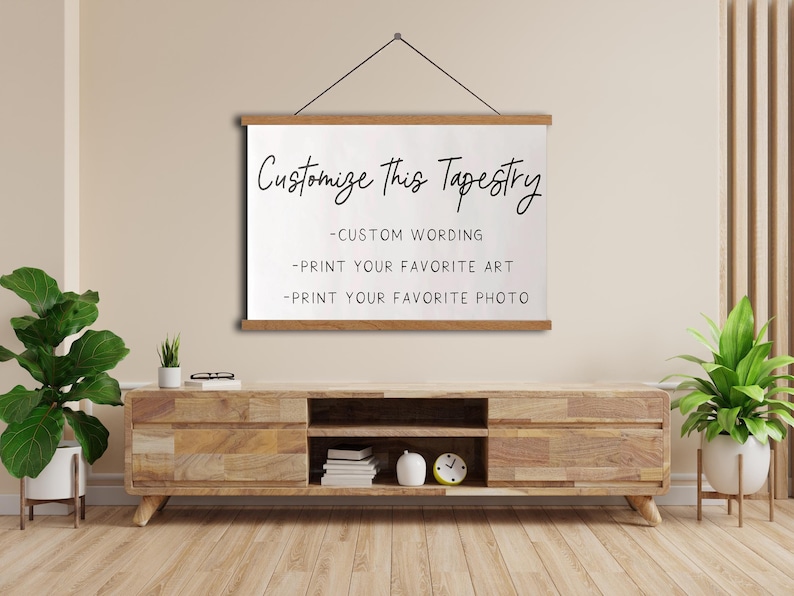 Op de afbeelding: Een wit wandkleed dat aan een muur hangt met de tekst "Customize This Tapestry" en een lijst met aanpassingsmogelijkheden: - Eigen tekst - Print je favoriete kunst - Print je favoriete foto.