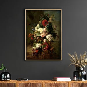 May include: A framed oil painting of a still life featuring a bouquet of colorful flowers in a vase. The flowers include roses, carnations, and other blooms in shades of red, white, and pink. The painting is set against a dark green background.
