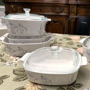 May include: A collection of white casserole dishes with clear glass lids. The dishes feature a delicate floral design in blue and green. The set includes various sizes, perfect for baking and serving.