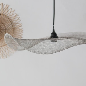 May include: A modern, wavy, silver mesh pendant light fixture with a black cord and a black metal canopy.