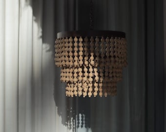 May include: A decorative chandelier featuring a dark metal frame and multiple wooden beads. The light-coloured beads hang in cascading layers, creating a textured lighting fixture. The chandelier is suspended from a chain.