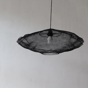 Può includere: Lampada a sospensione in rete metallica nera con una singola lampadina appesa a un cavo nero.