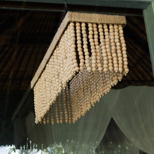 May include: A wooden bead chandelier with a natural wood finish. The beads are strung together in a cascading pattern, creating a unique and stylish look.
