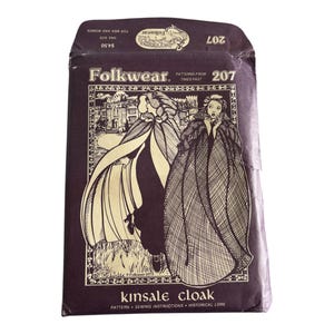May include: A brown paper envelope with a gold and white illustration of two people wearing cloaks. The envelope is labeled "Folkwear" and "Kinsale Cloak".