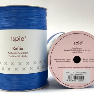 Puede incluir: Un carrete de hilo de rafia Ispie azul brillante hecho de fibra vegetal 100% viscosa. La etiqueta muestra el texto Ispie, Raffia, Authentic Plant Fiber, The Most Silky Raffia e incluye un código de barras con el código de color 112C Mediterranean.