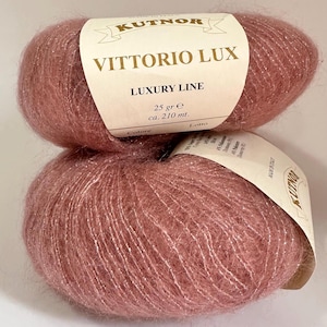 May include: Two skeins of pink yarn with silver glitter threads. The label reads "KUTNOR Vittorio Lux Luxury Line 25 gr e ca. 210 mt."