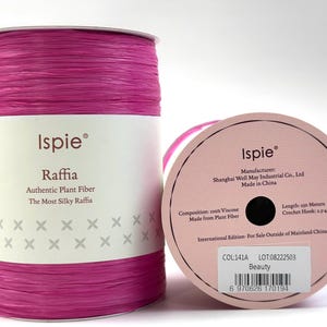 May include: A spool of bright pink Ispie raffia yarn made of 100% viscose plant fiber. The label indicates a length of 250 meters and a recommended crochet hook size of 2.5-4mm. The color is labeled as Beauty, lot number 08222503, color 141A.