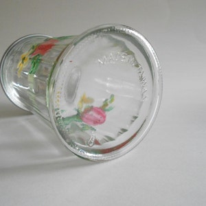 May include: A clear glass vase with a floral design painted on the side. The vase has a textured surface and the words "Made in Australia" are printed on the bottom.