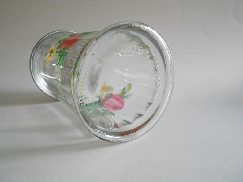 May include: A clear glass vase with a floral design painted on the side. The vase has a textured surface and the words "Made in Australia" are printed on the bottom.