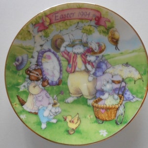 Pode incluir: Um prato de cer&acirc;mica decorativo com fundo verde e uma cena de coelhos e outros animais. O prato tem uma borda dourada e o texto "Easter 1994" em rosa.