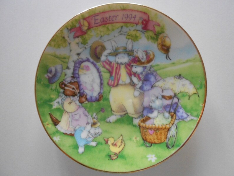 Pode incluir: Um prato de cer&acirc;mica decorativo com fundo verde e uma cena de coelhos e outros animais. O prato tem uma borda dourada e o texto "Easter 1994" em rosa.