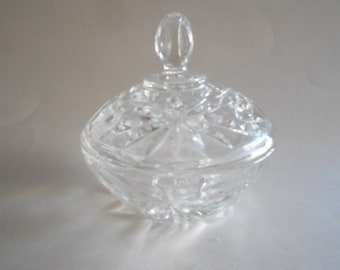 May include: A clear glass candy dish with a lid. The dish has a cut glass design and the lid has a knob on top.