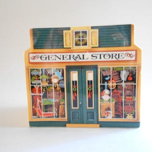 May include: A vintage-style general store building with a green roof and yellow trim. The windows are decorated with Christmas-themed items and the sign reads "GENERAL STORE".