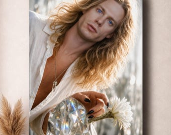 May include: A portrait of a person with long blonde hair and blue eyes wearing a white button-down shirt and a crystal pendant necklace. The person has black fingernails and is holding a white flower near a large, faceted glass crystal.
