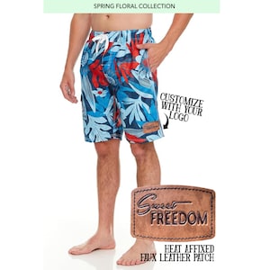 May include: Blue and red floral print swim trunks with a brown leather patch that says "Sweet Freedom".